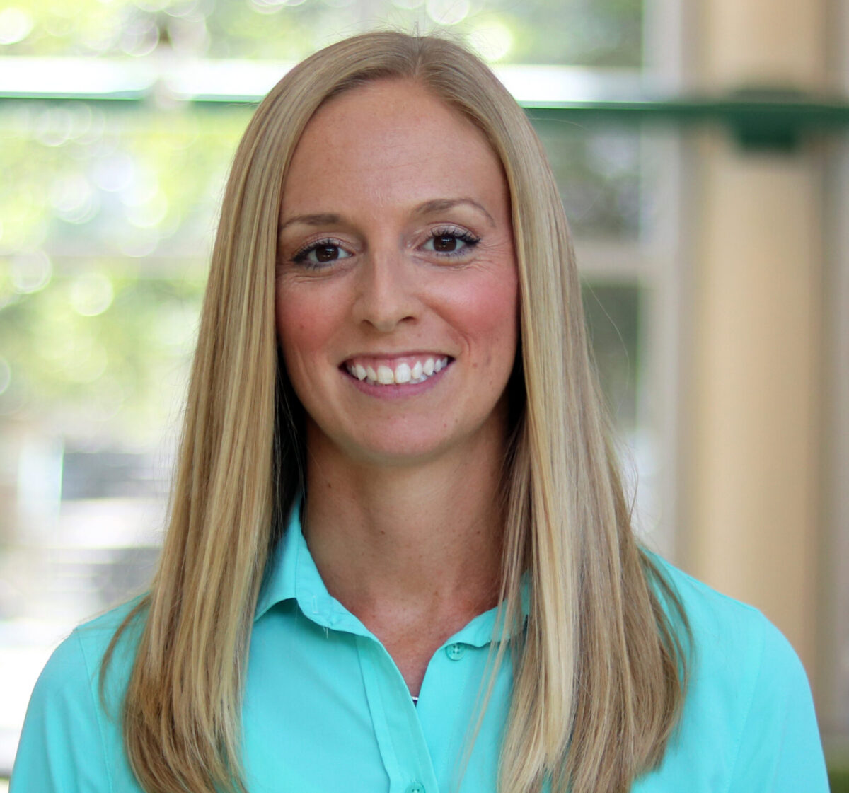 Woman with shoulder-length blond hair smiles at the camera.