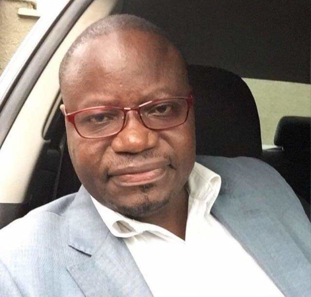 Man wearing glasses and a gray suit gazes at camera.