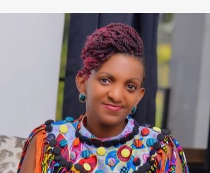 A woman with earrings and a brightly colored shirt smiles at the camera.