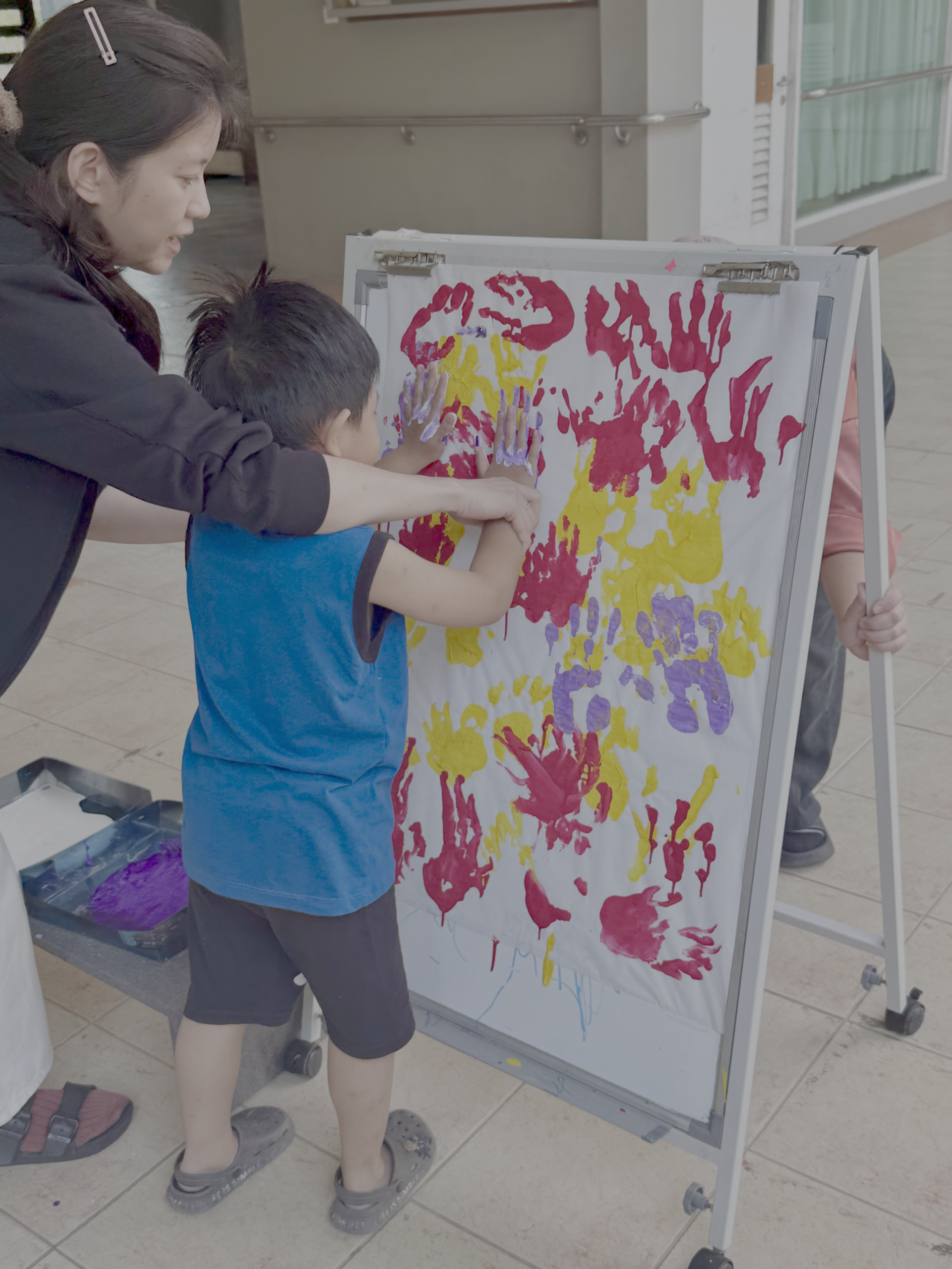 a child finger painting with their teacher