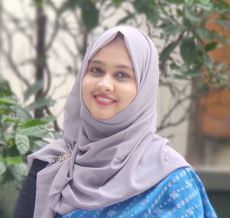 A woman wearing a hijab smiles at the camera.