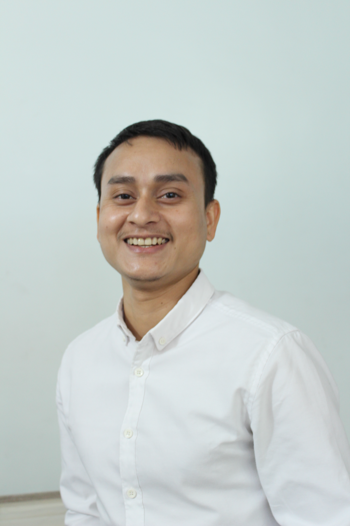 A man in a white shirt smiles at the camera.